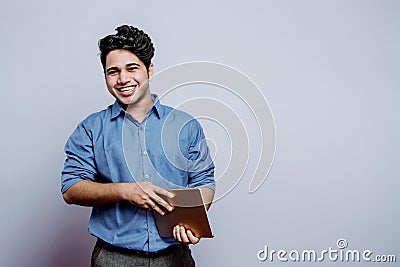 Â Joyful young male laughing out hysterically at funnyÂ joke with a teary eyes holding a digital tablet in hand Stock Photo